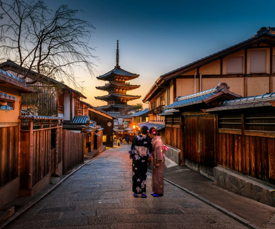two women in purple and pink kimono standing on street
